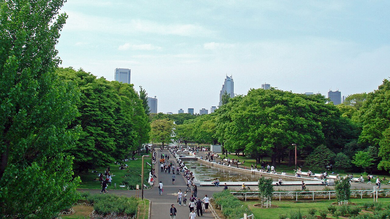 噴水と並木道、奥にビル群が見える広い公園